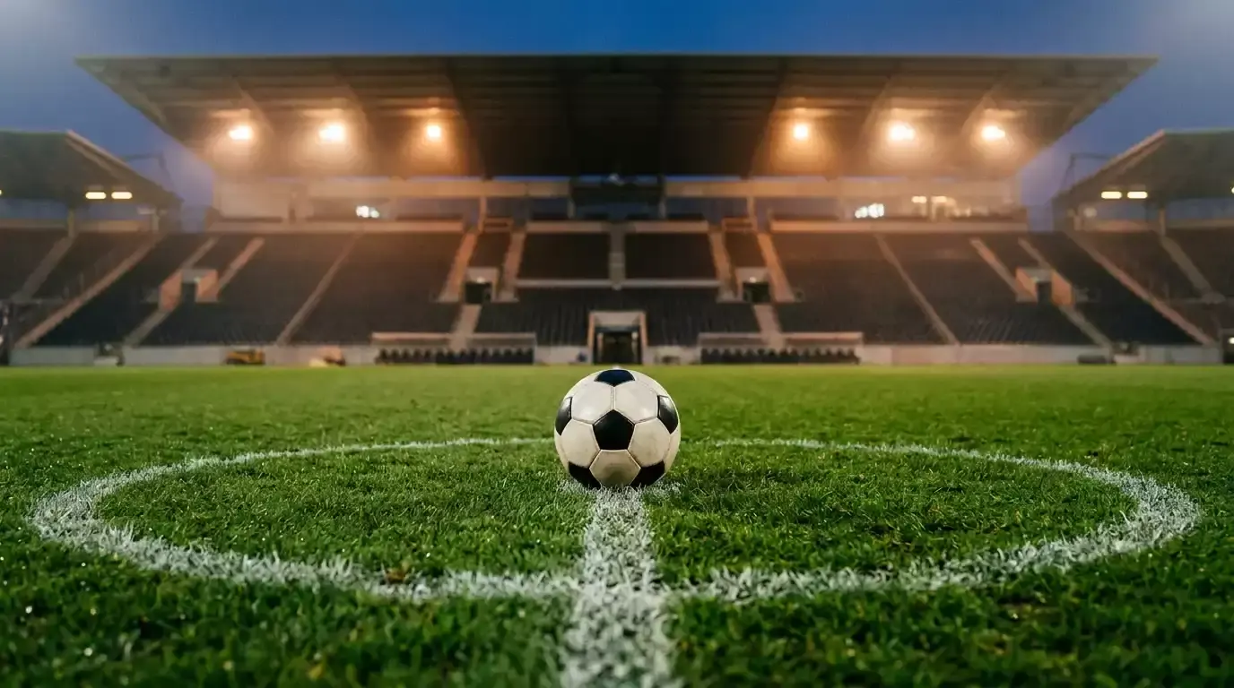 Fodbold på pitch under kunstig aftenlys ved stadion