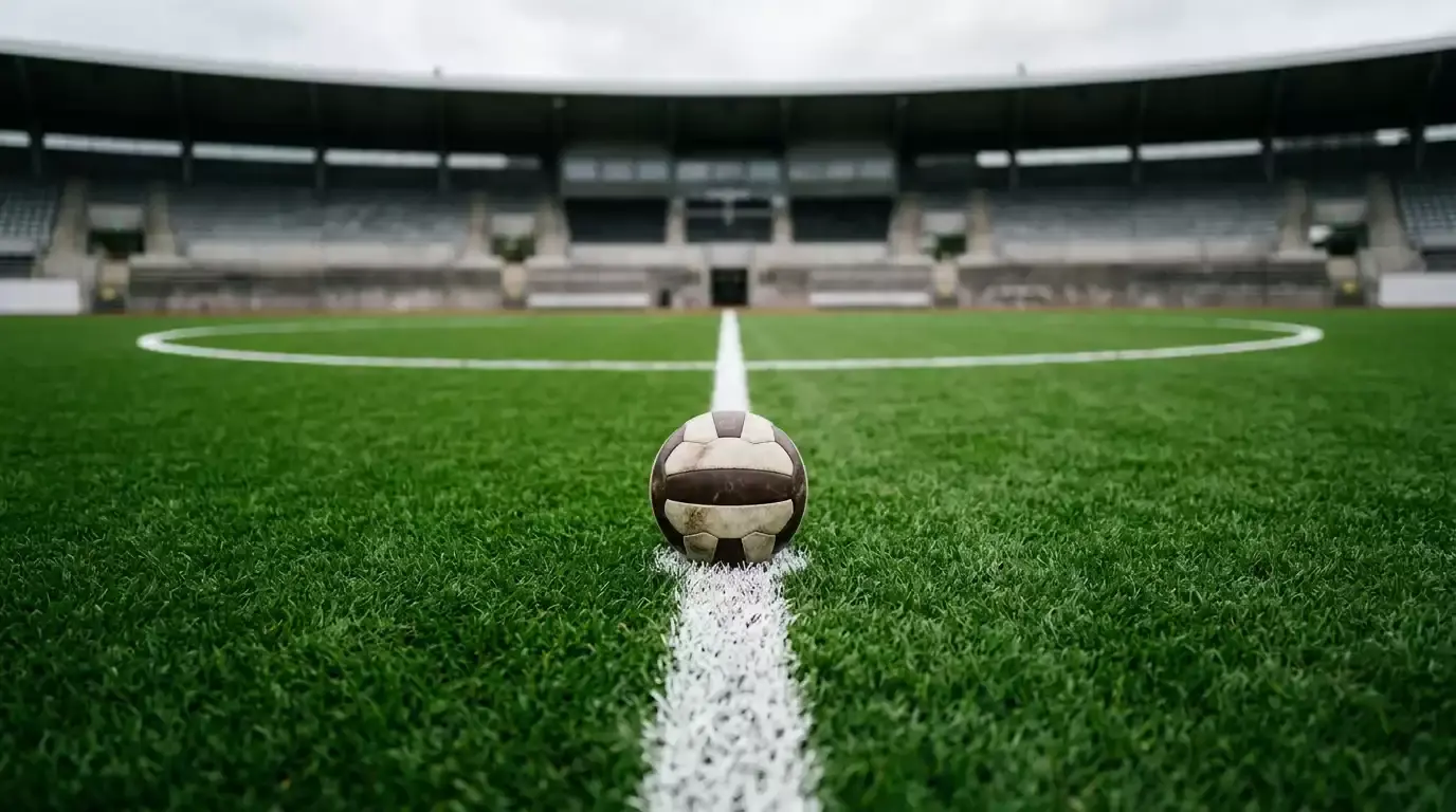 Fodboldstadion-græsplæne med fodbold og tomme tilskuerrækker i baggrunden