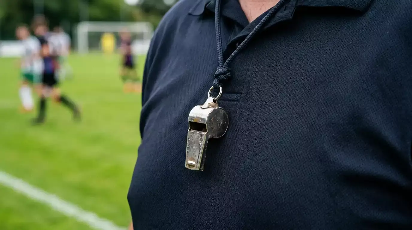 Fodbolddommerfløjte hænger om halsen med pitch i baggrund